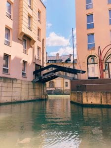 An image of a canal with a triangular bridge connecting two buildings.